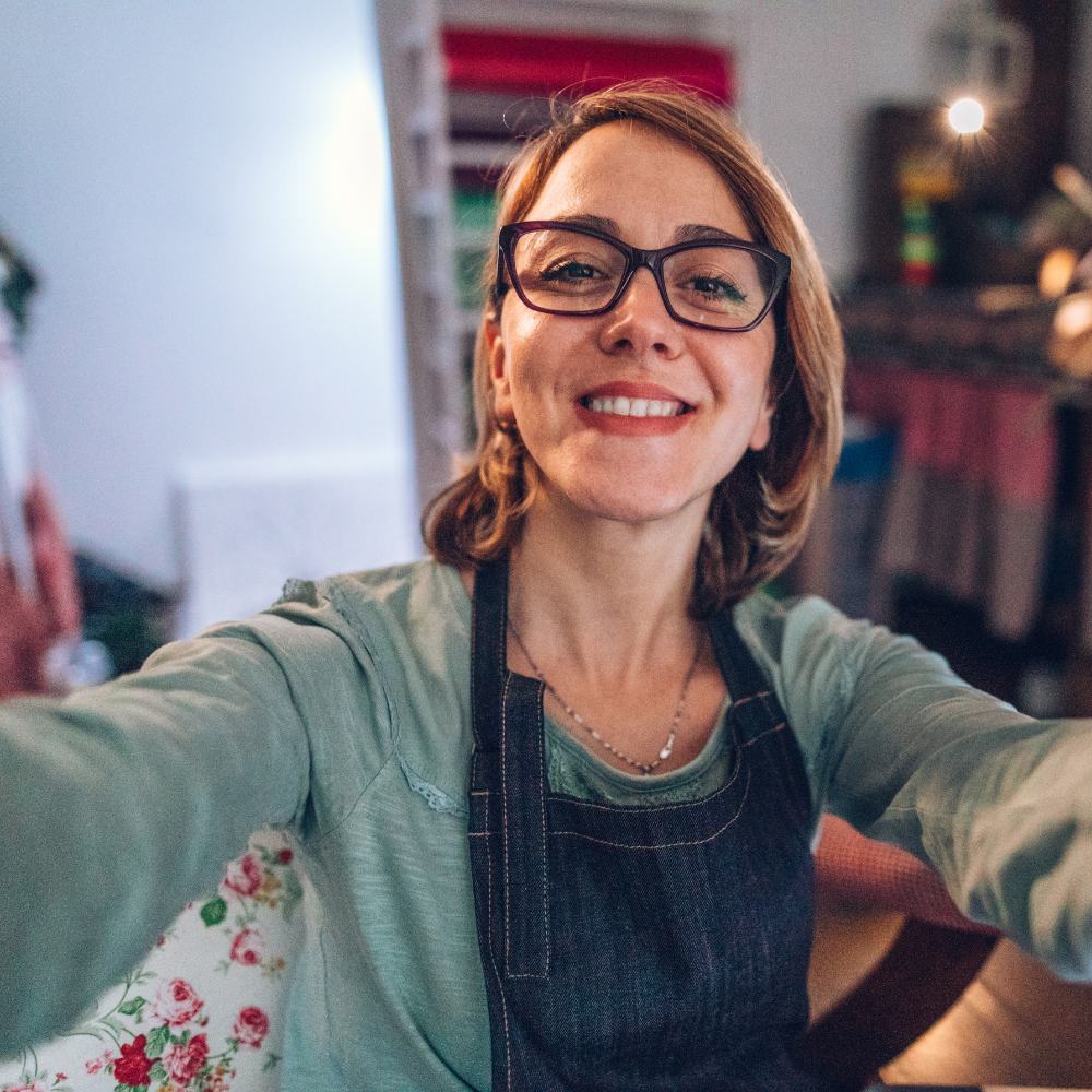Person taking a selfie, wearing glasses and an apron.
