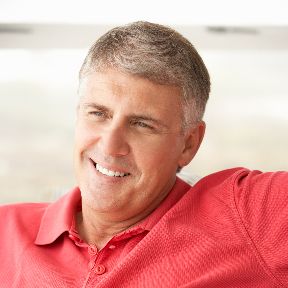 Man in a red polo shirt smiling, with blurred background.
