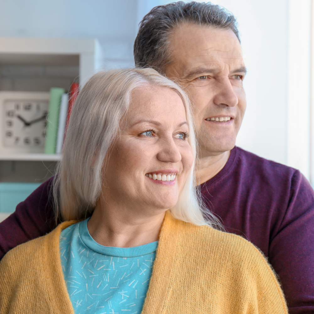 A happy couple smiling while looking out a window.