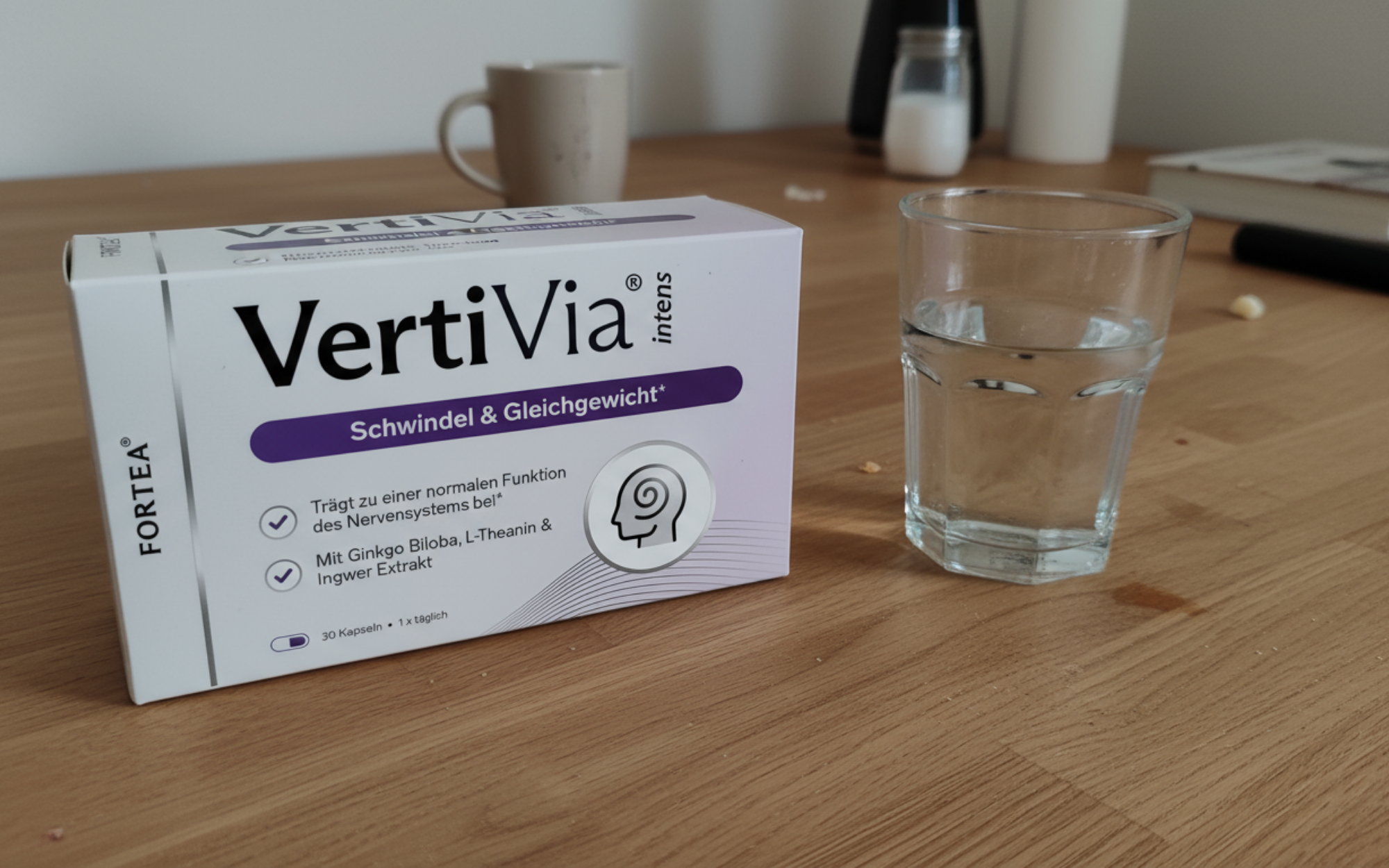 Box of VertiVia and glass of water on a wooden table.