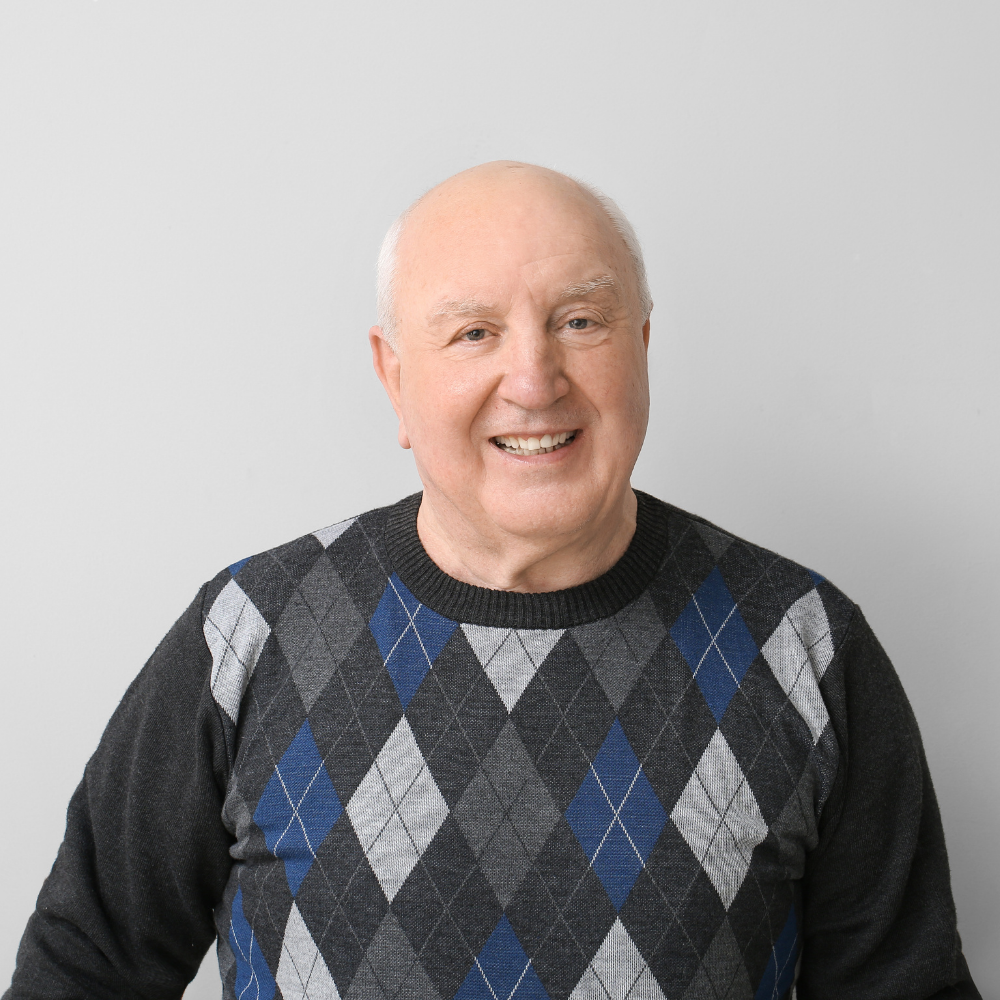 Smiling man in argyle sweater against plain background.