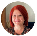 Person with red hair smiling, wearing a patterned blouse.