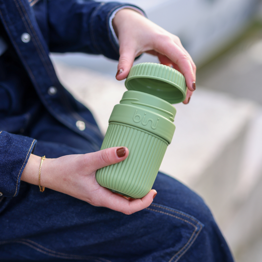 Person unscrewing a green, ribbed, reusable container lid.