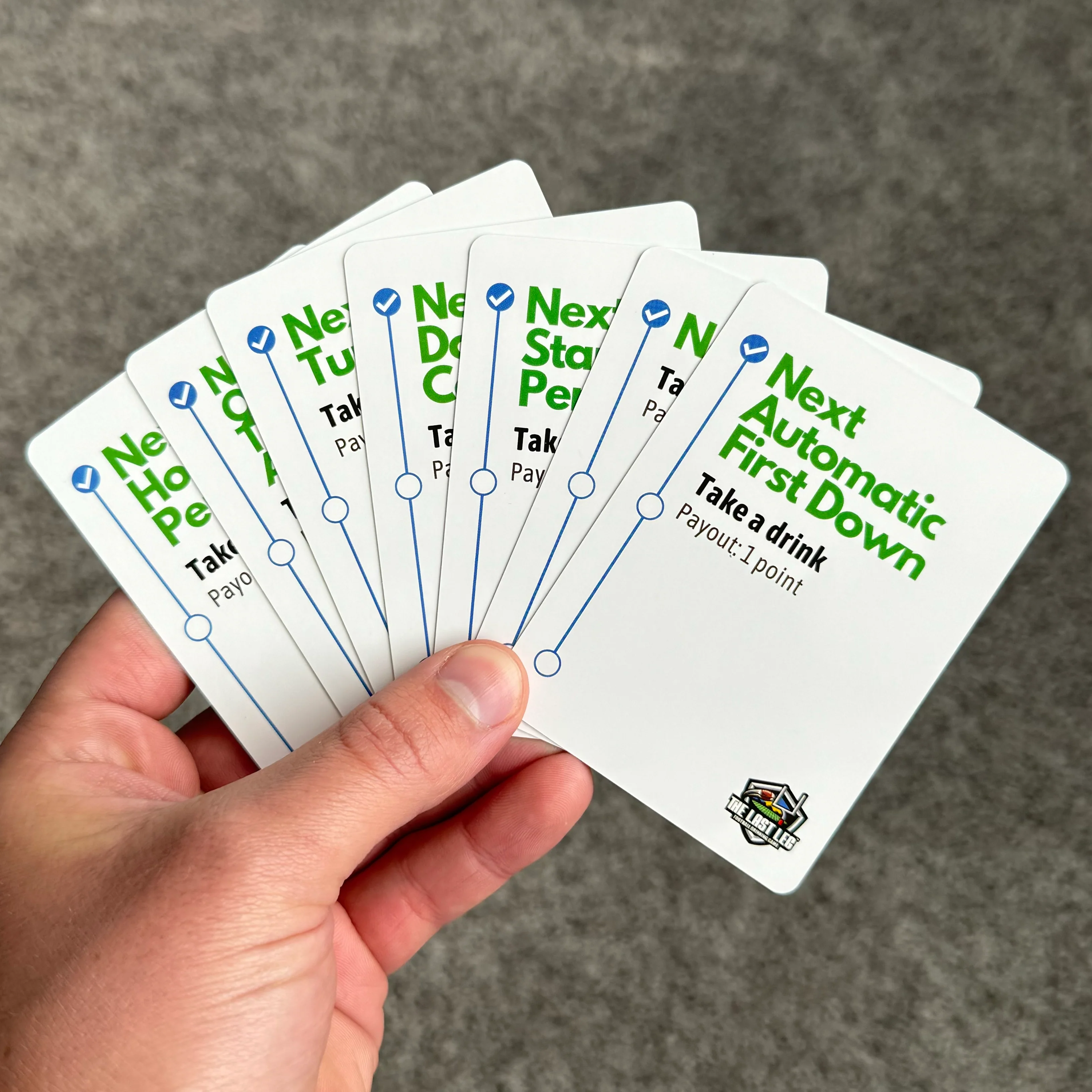 A hand holding several cards with text in green and black.