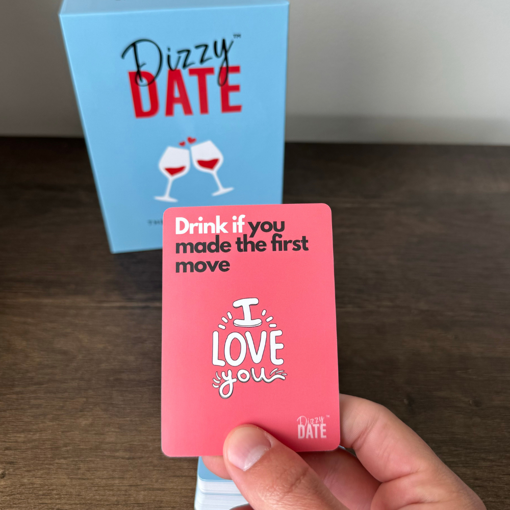 Hand holding a card with 'Drink if you made the first move' text.