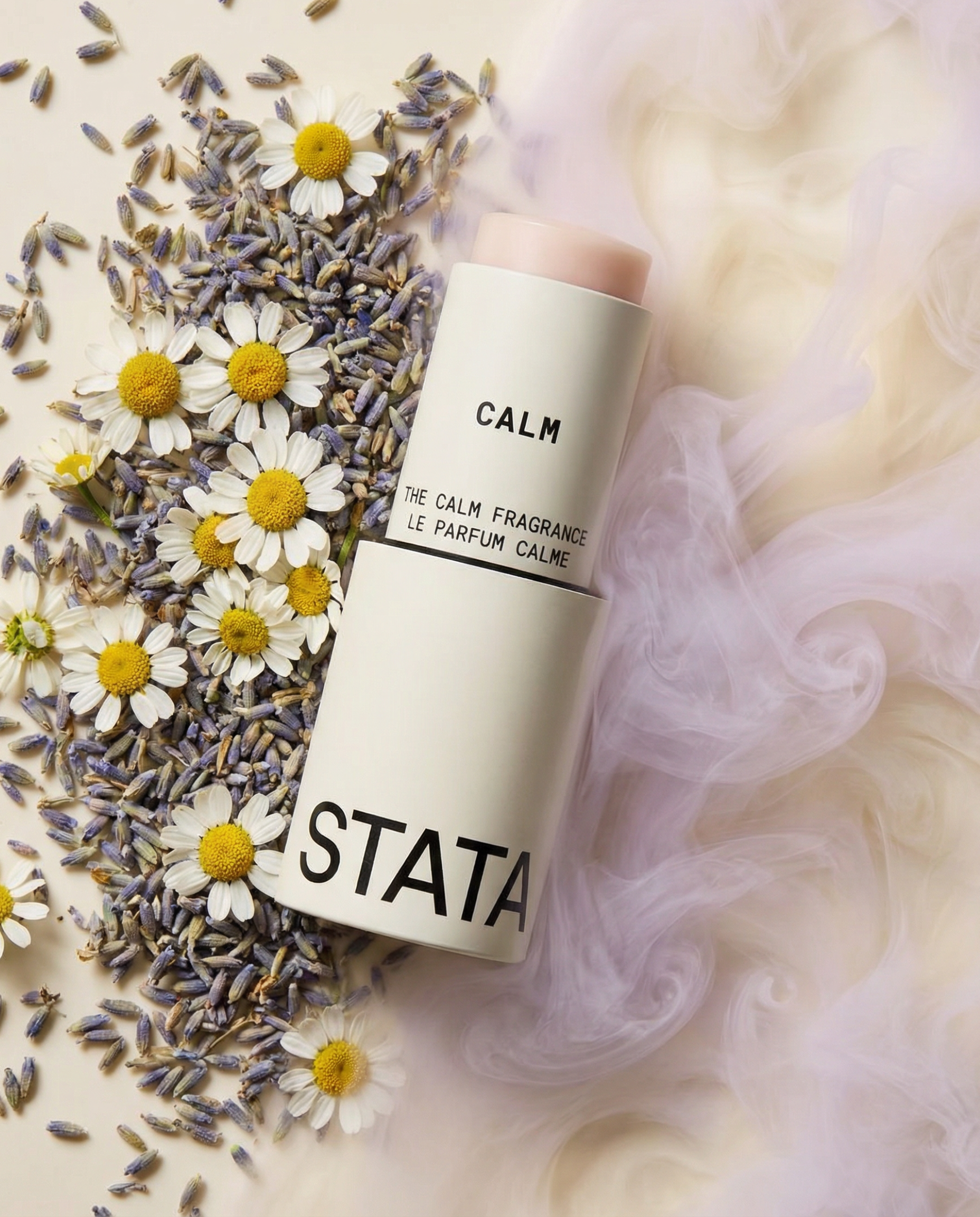 A white tube of 'Calm' fragrance stick lies on a bed of lavender and chamomile flowers.