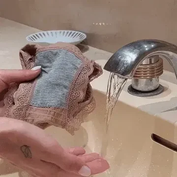 Hand washing delicate lace underwear under a running faucet.