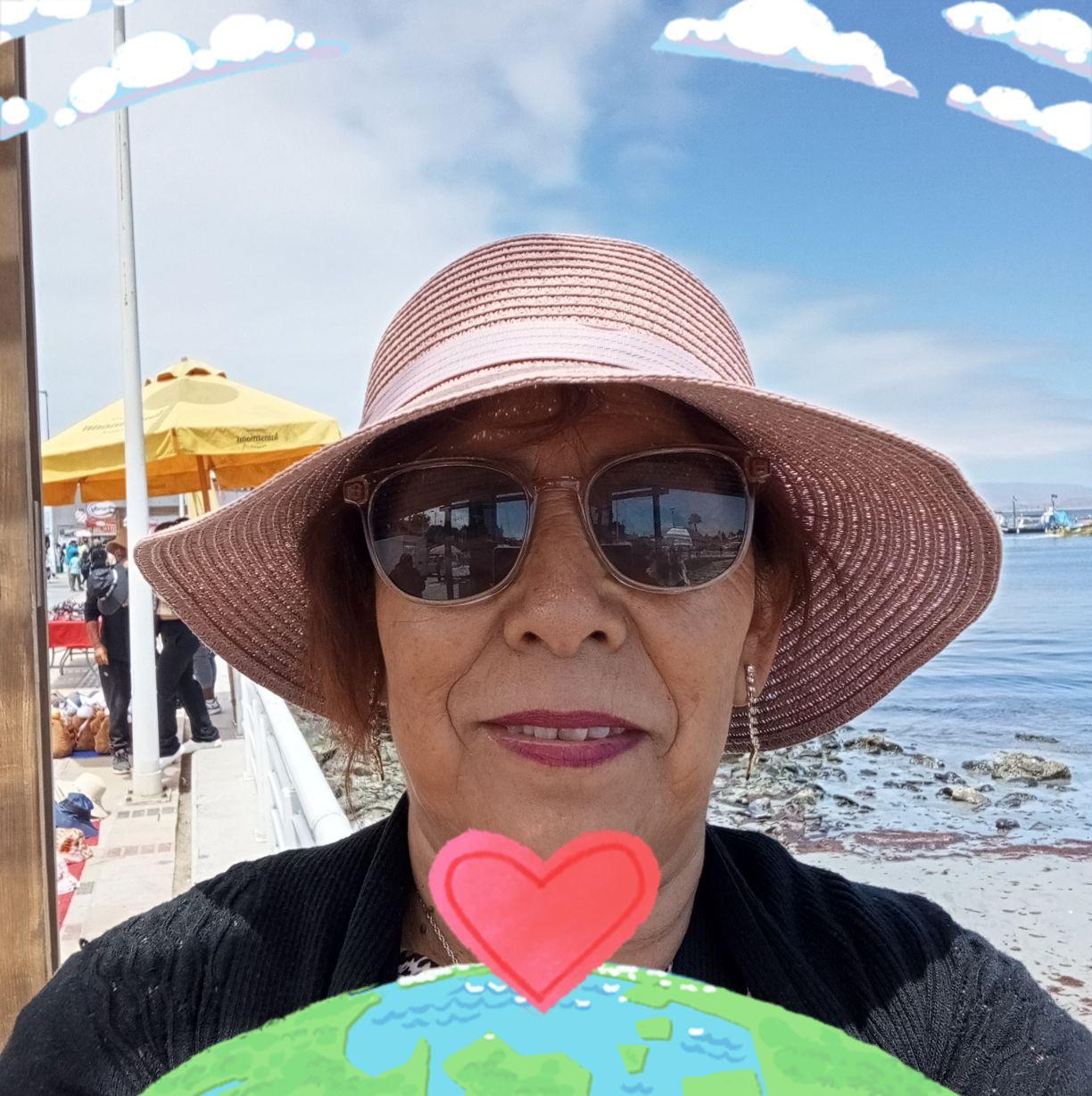 A person wearing sunglasses and a sunhat by the seaside with a heart and Earth graphic overlay.