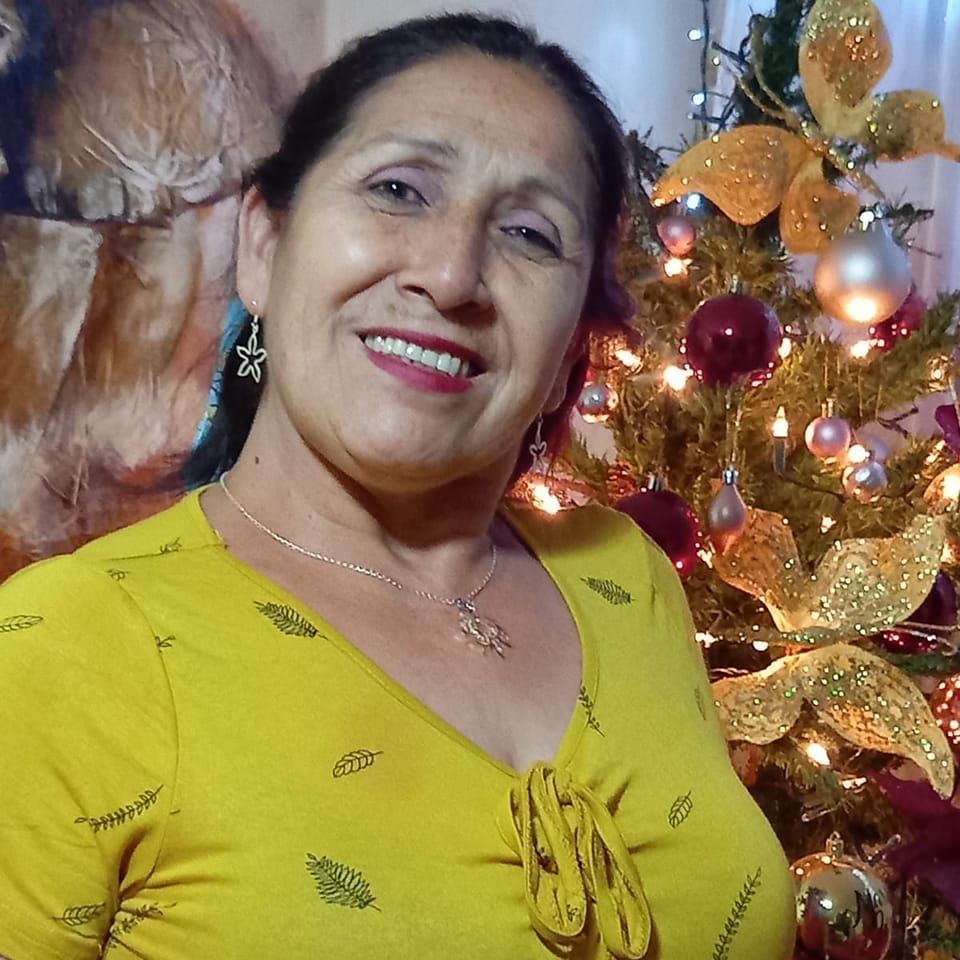 Woman smiling in front of a decorated Christmas tree.