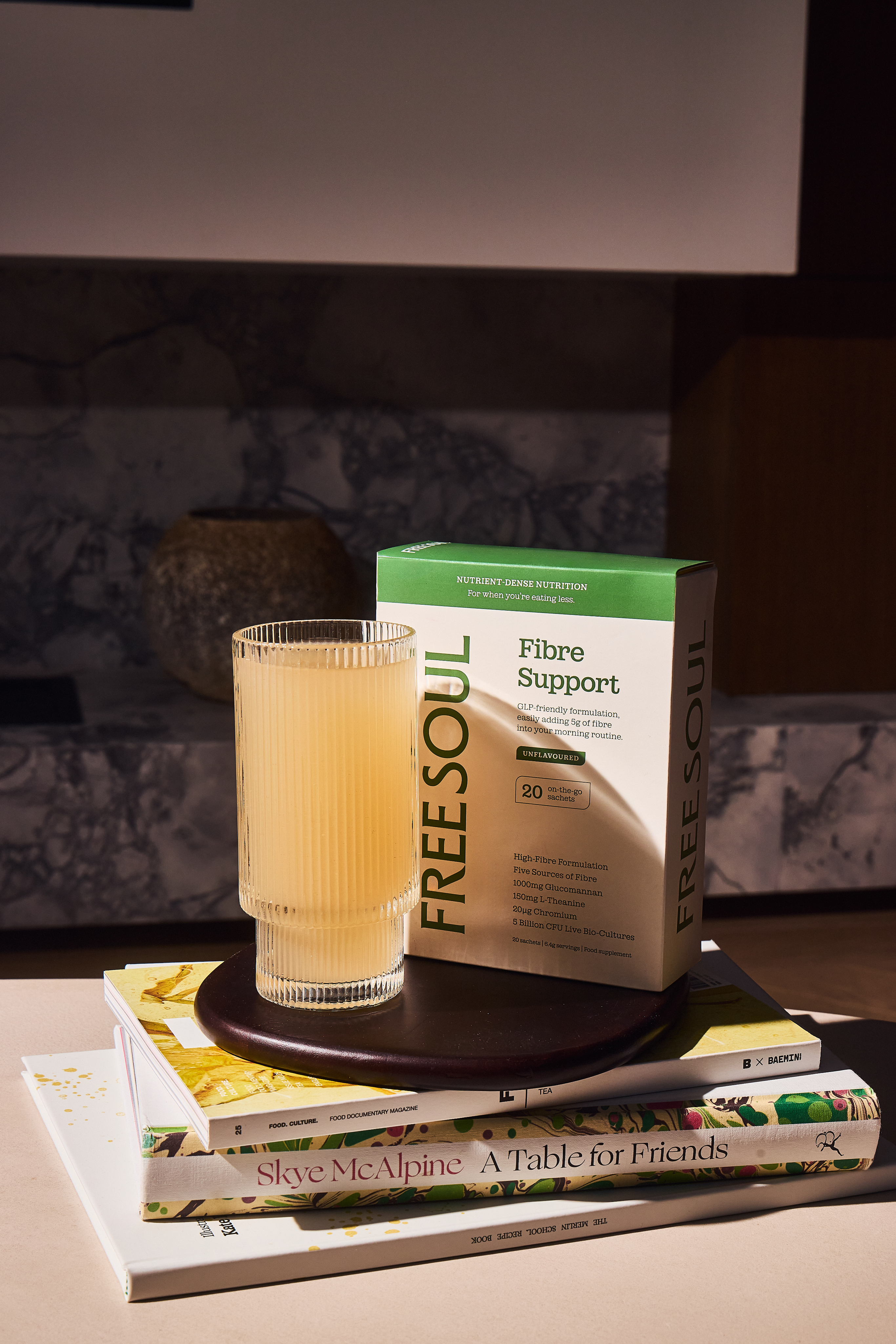 A box of Freesoul Fibre Support sits on a stack of books next to a prepared drink.