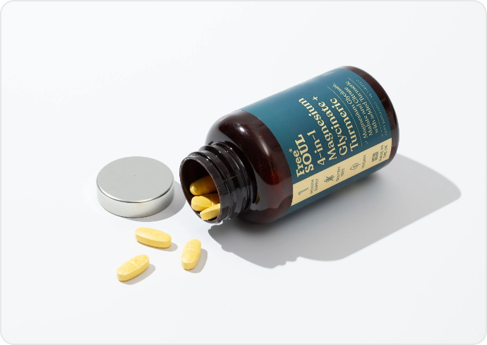 Open bottle of yellow pills with scattered tablets on white background.