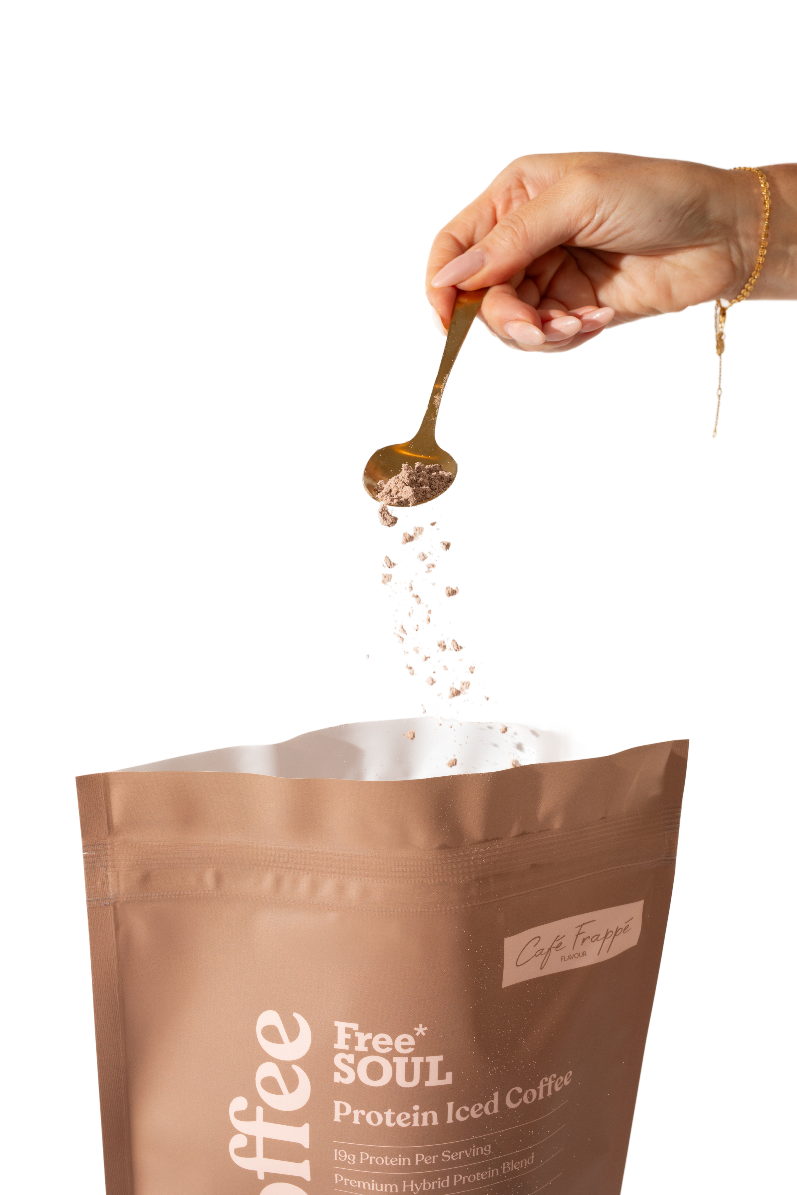 A hand sprinkling coffee powder into a protein iced coffee pouch.