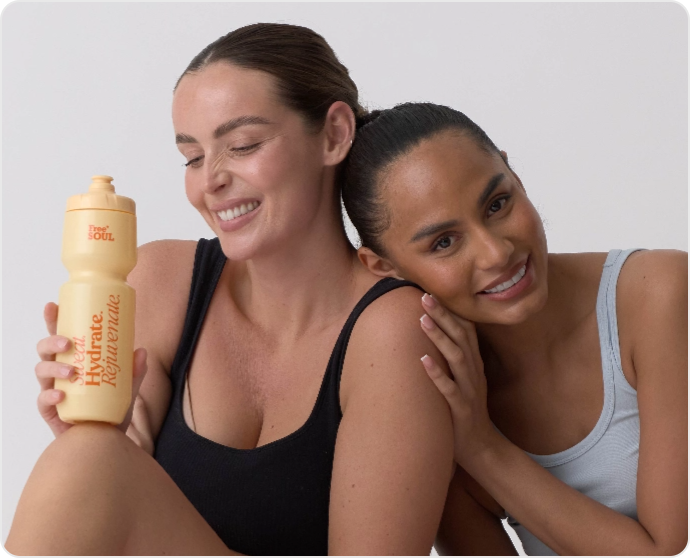 Two women smiling, one holding a yellow water bottle.