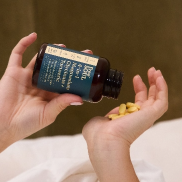 Hands pouring yellow pills from a bottle into a palm.