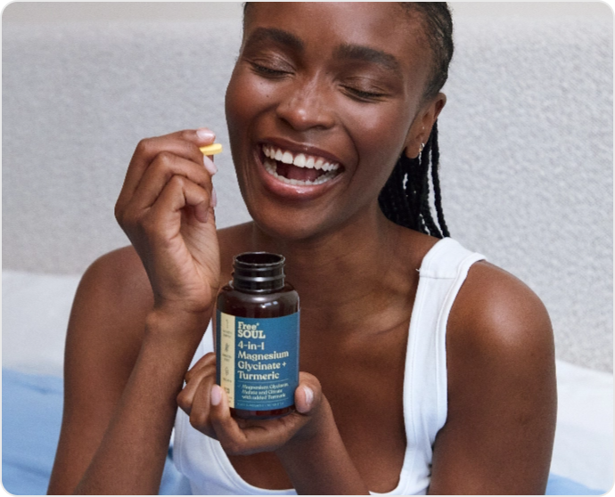 Person smiling, holding a supplement bottle and a capsule.