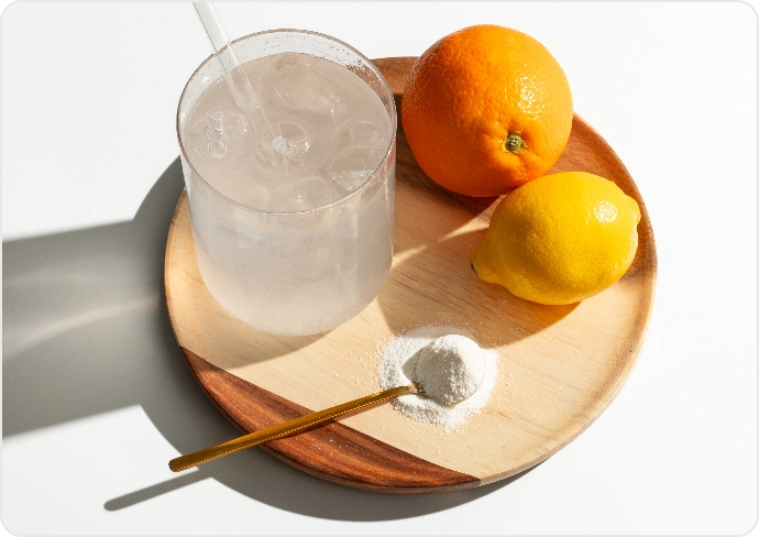 Glass of iced water, orange, lemon, and powder on a wooden tray.