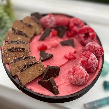 Smoothie bowl with chocolate pieces and raspberries.