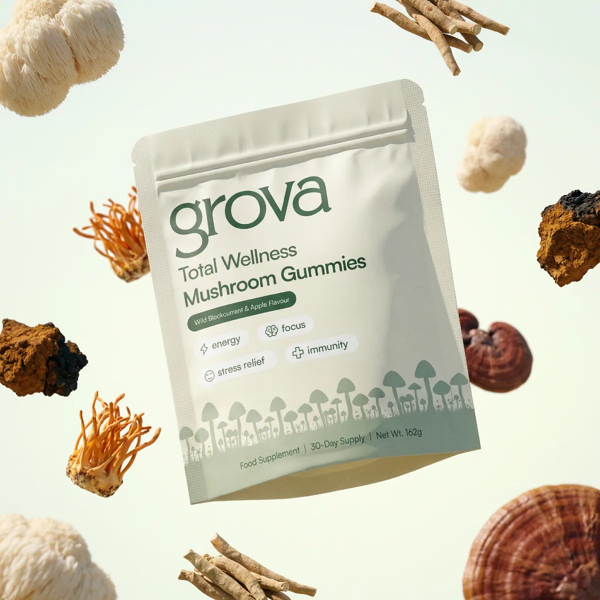 A pouch of grova Total Wellness Mushroom Gummies surrounded by various mushrooms and roots against a white background.