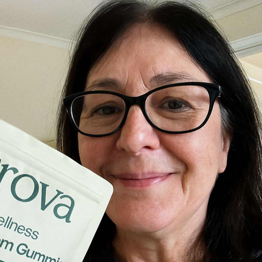 Older woman wearing glasses holding Grova Total Wellness Gummies, sharing her positive wellness experience.