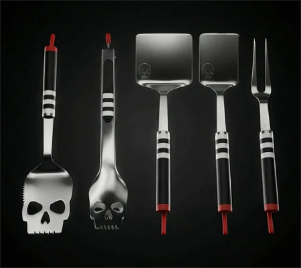 A set of five stainless steel barbecue tools with black handles and skull designs against a black background.