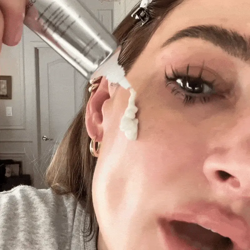 Woman applying cream to her face near the eye area.