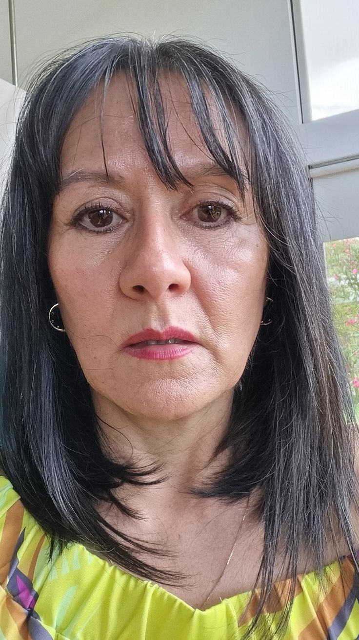 A woman with dark hair and a yellow top, looking directly at the camera.