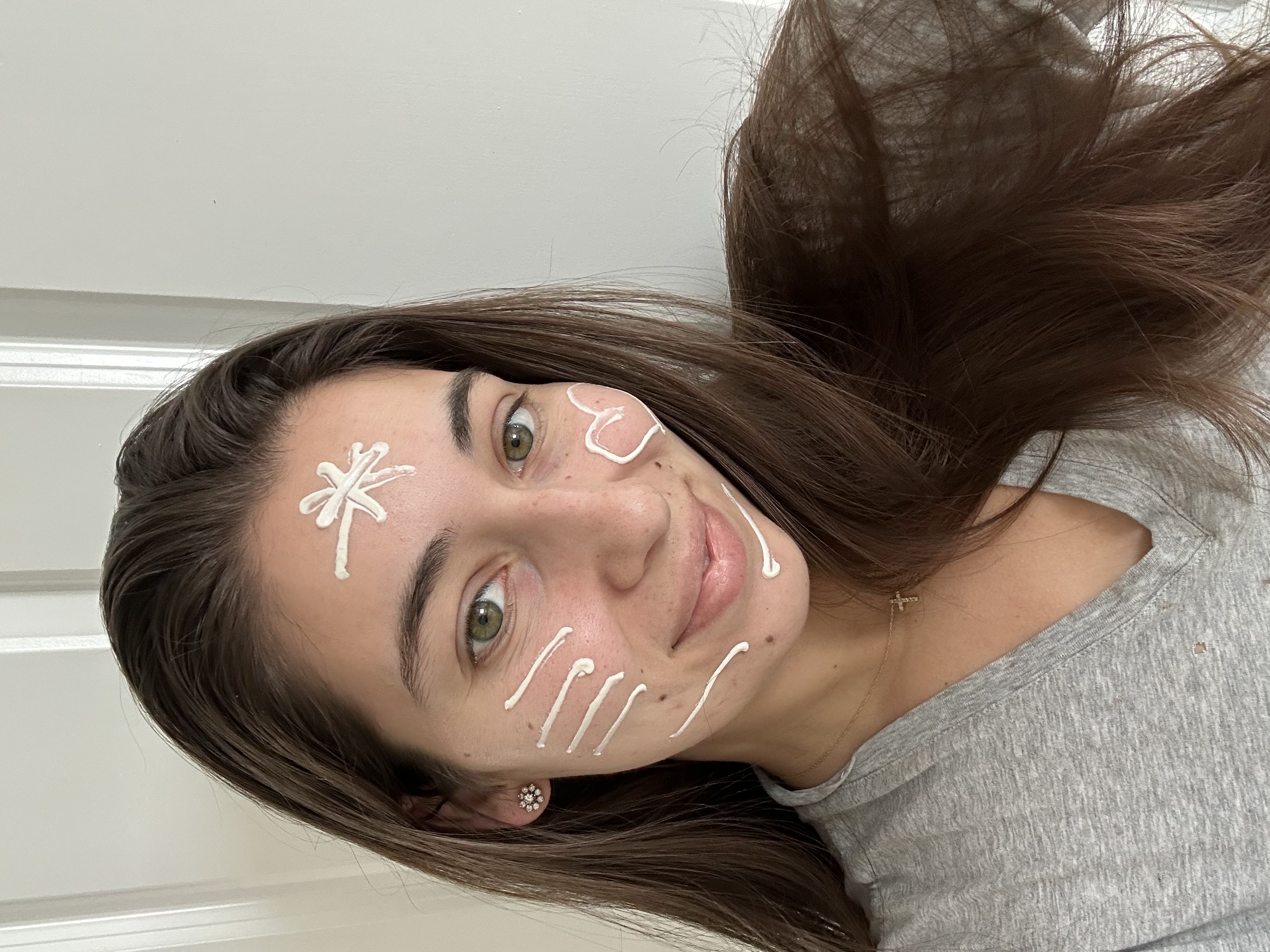 Person with designs on face using white lotion.
