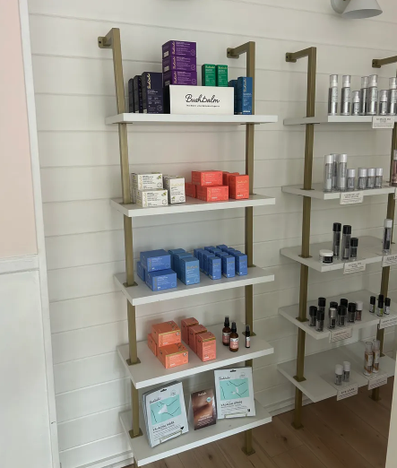 Skincare and beauty products neatly arranged on multi-level wall shelves in a retail store.