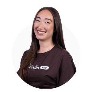 Headshot of a smiling woman with long dark hair wearing a brown t-shirt with a logo.