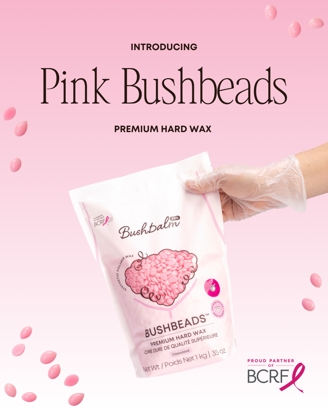 A gloved hand holds a bag of Bushbalm Pink Bushbeads hard wax against a pink background.