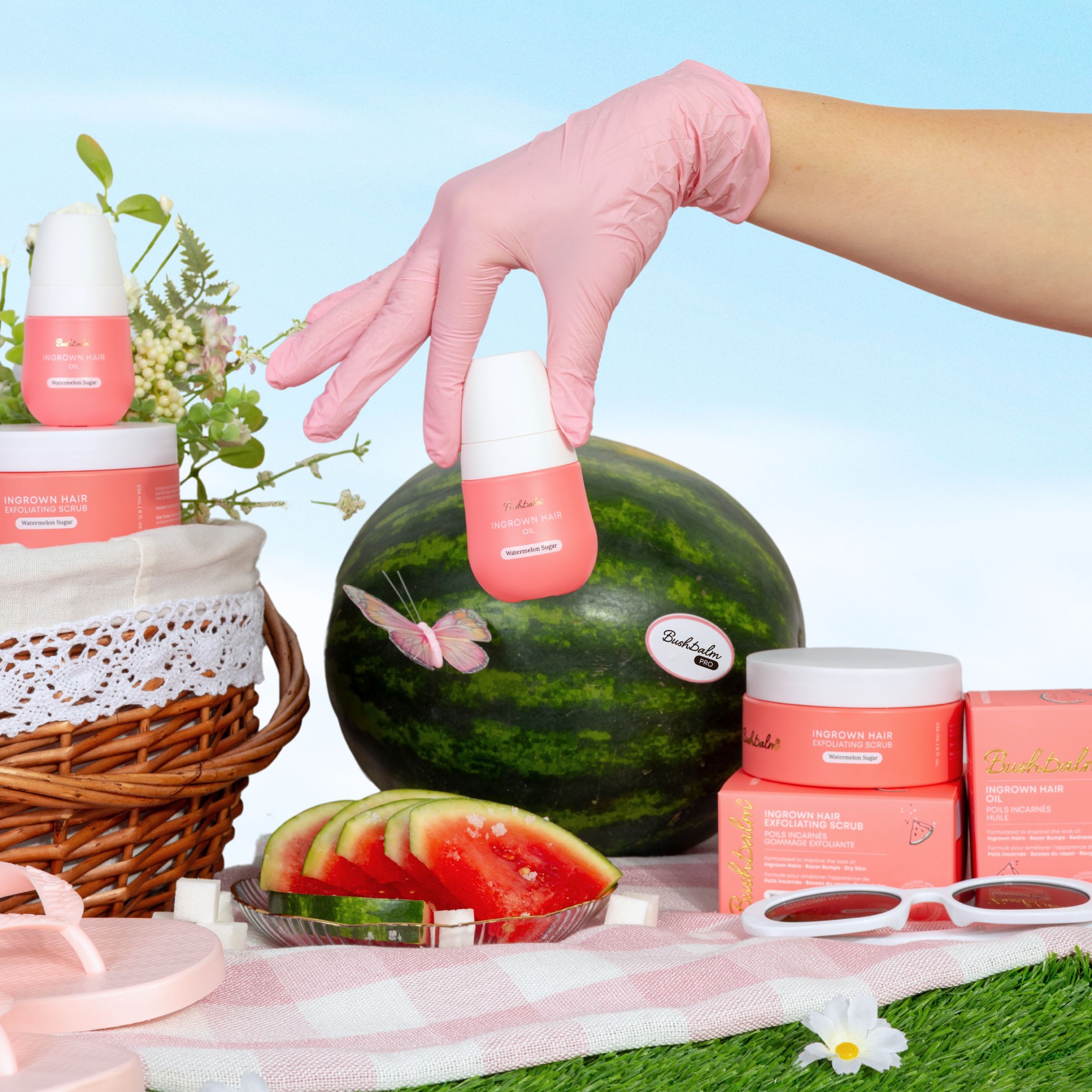 Pink-gloved hand holding skincare product over a picnic scene with watermelon and flowers.