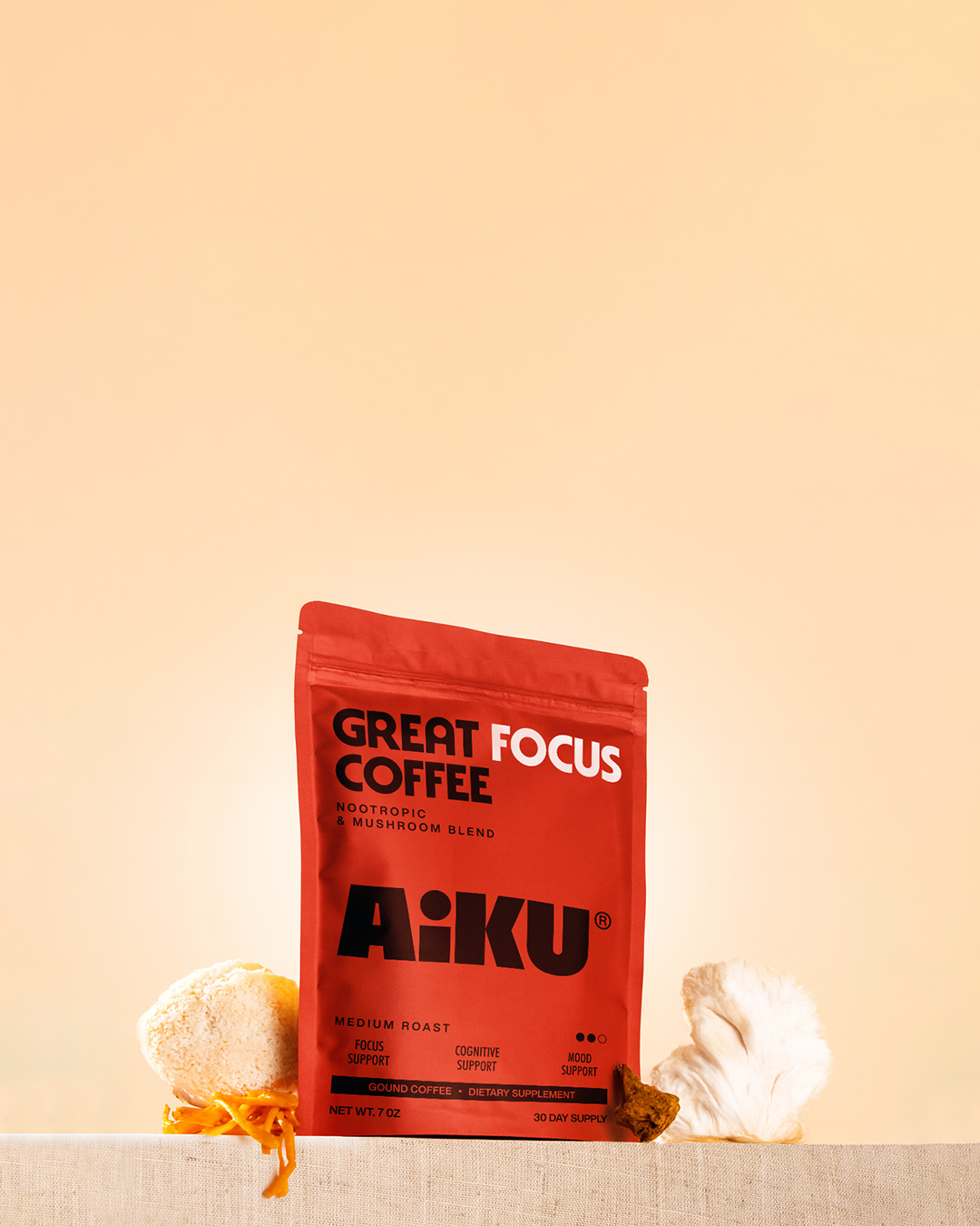 A red bag of A:IKU Great Focus Coffee on a stone pedestal with mushrooms and coffee beans.