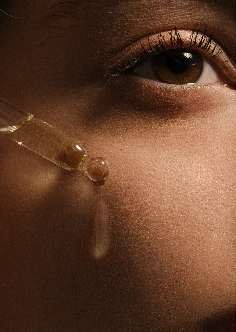 Close-up of an eye with a dropper applying liquid to the skin.