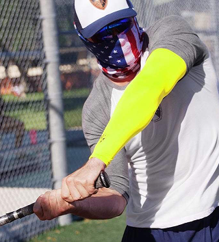 Person swinging a baseball bat, wearing a mask and bright yellow sleeve.
