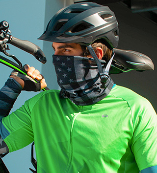 Cyclist in green shirt with helmet and face covering, holding a bicycle.
