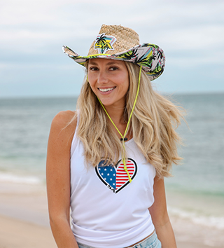 Woman in a straw hat and tank top on a beach.