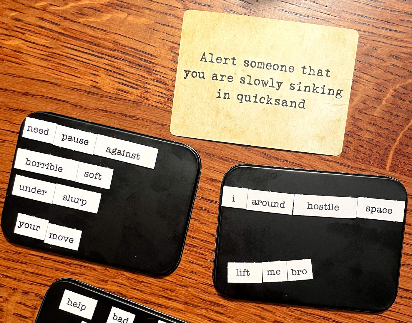 A prompt card for a word game sits on a table next to tins covered in word magnets.