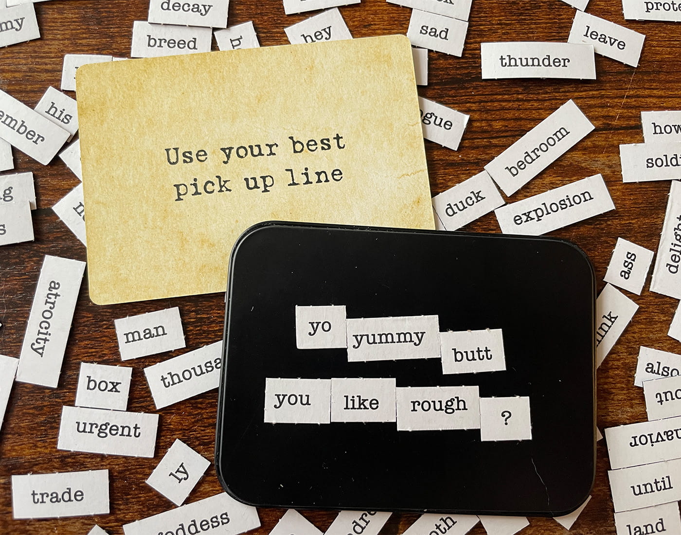 A card reading 'Use your best pick up line' surrounded by word cutouts on a wooden table.