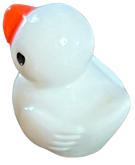 A small, glossy white figurine of a duck with an orange beak, viewed from a high angle.