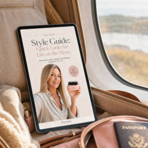 A tablet displaying a style guide rests in an open suitcase next to a passport on a train.