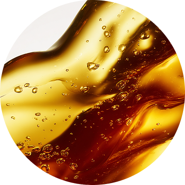 A circular close-up of a viscous, golden-amber liquid with many bubbles.