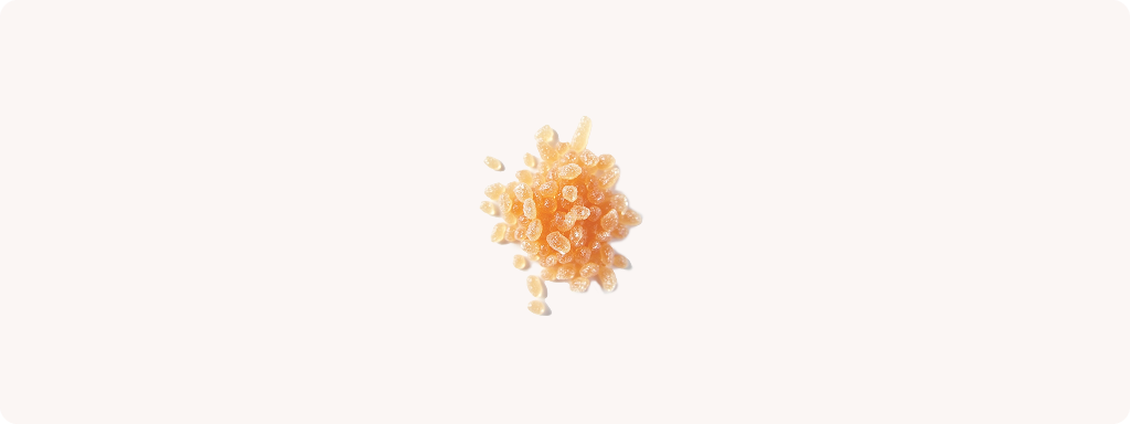 Cluster of small, translucent orange crystals on a white background.