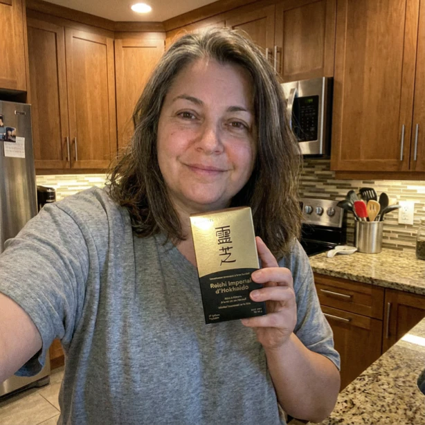 Person in kitchen holding a box with Asian characters on it.