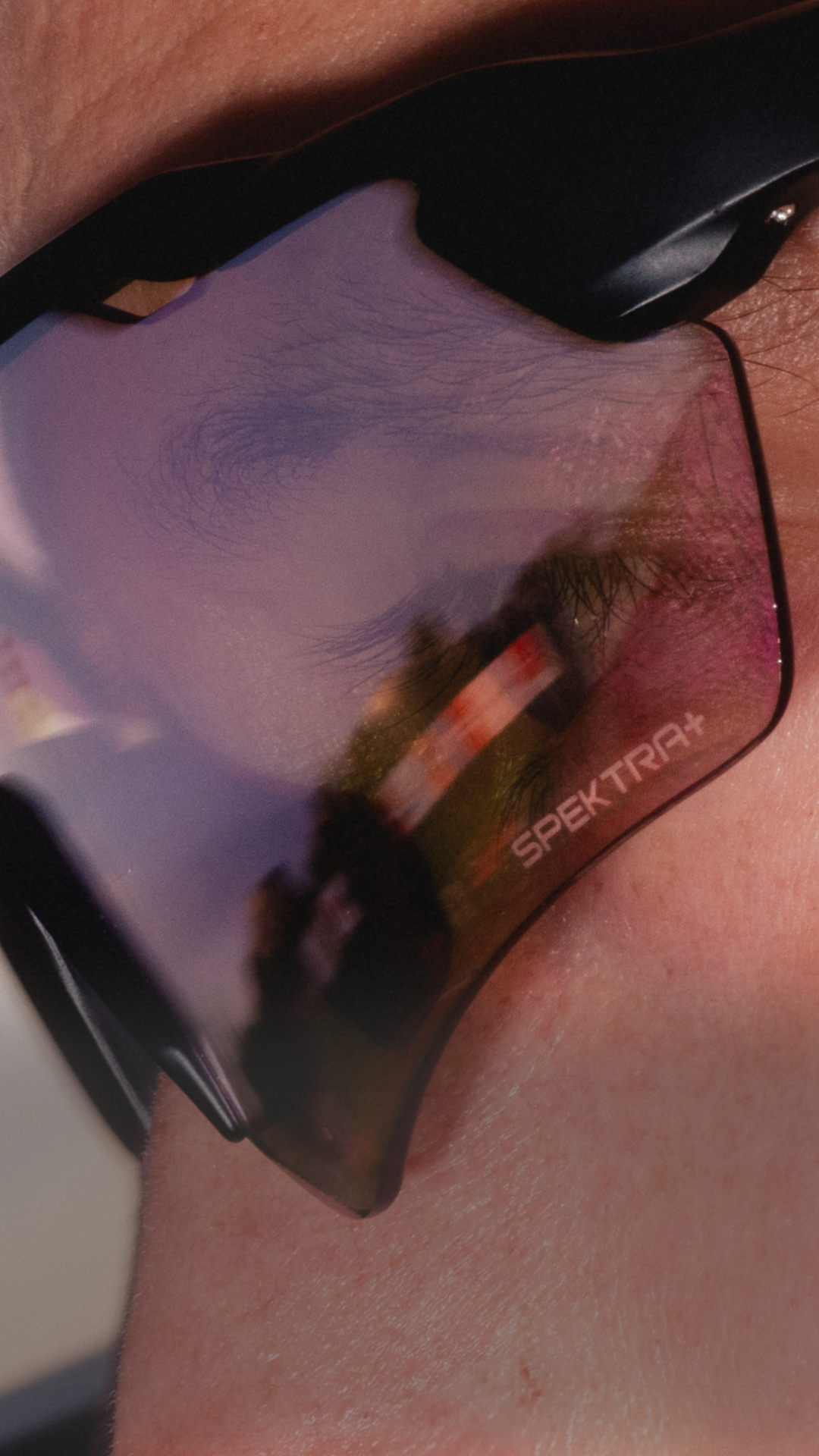 Close-up of reflective sunglasses with partial view of a face.