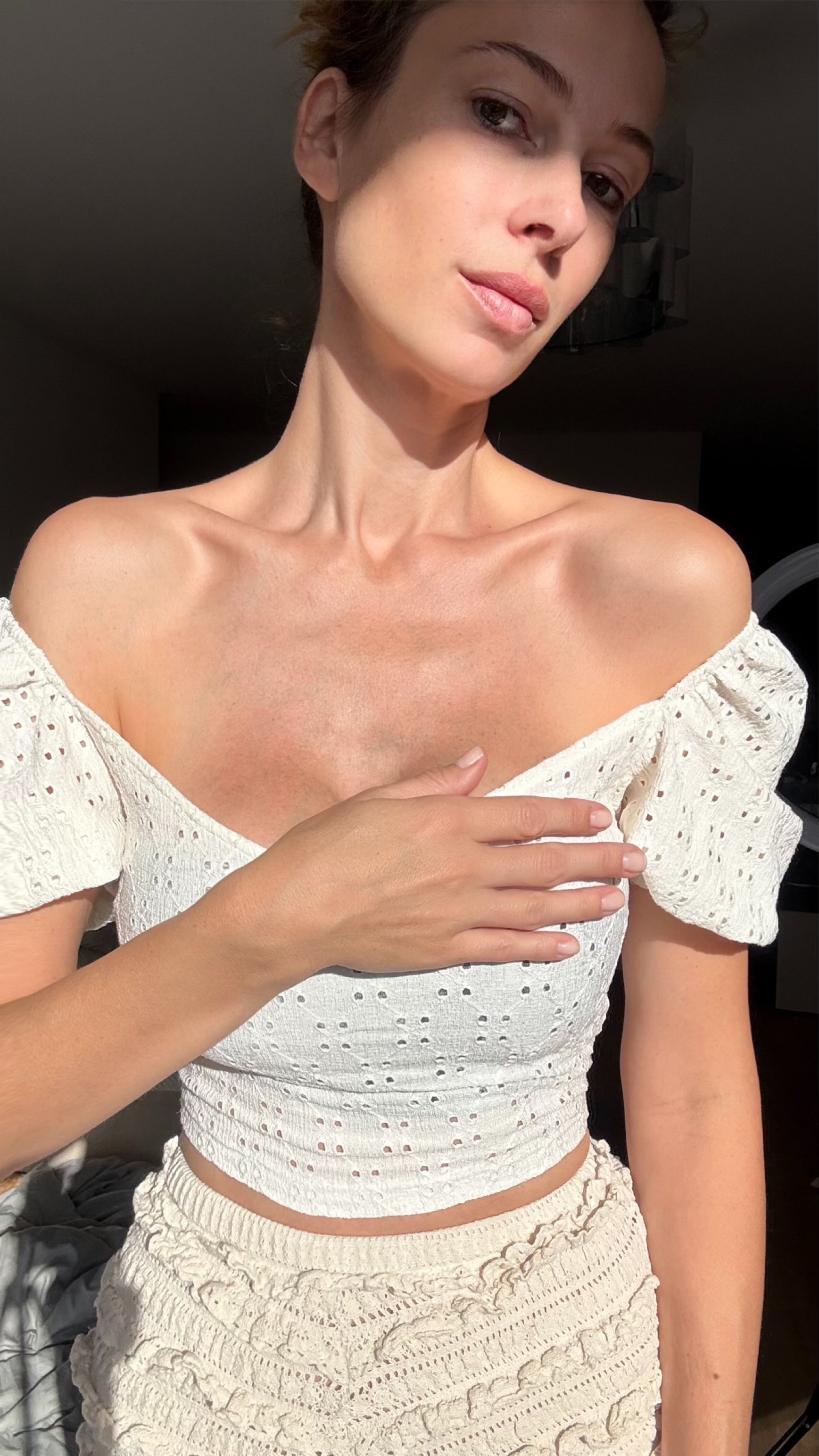 Person in white off-shoulder top, sunlight on face.