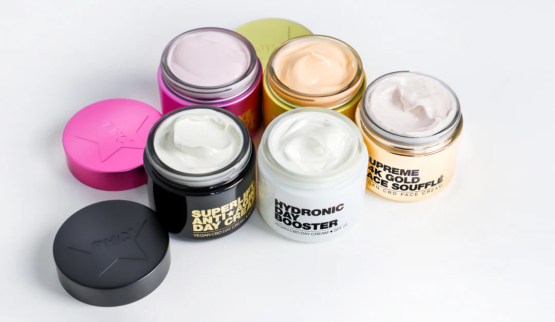 Five jars of face creams with colorful lids on a white background.