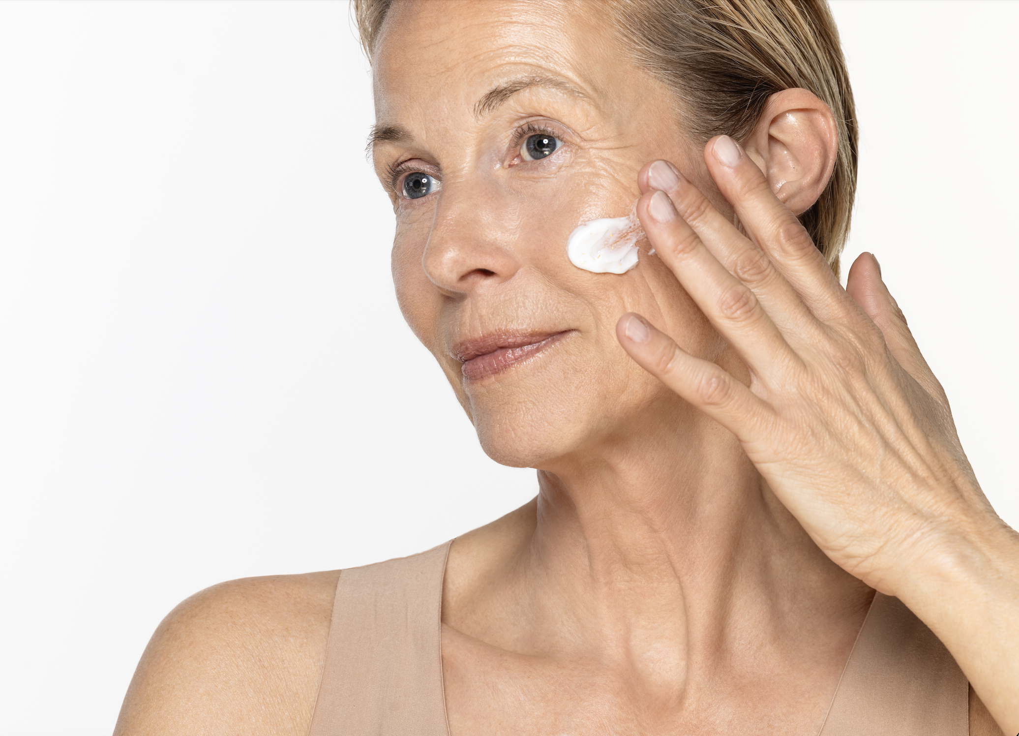 Person applying cream to face with fingers.