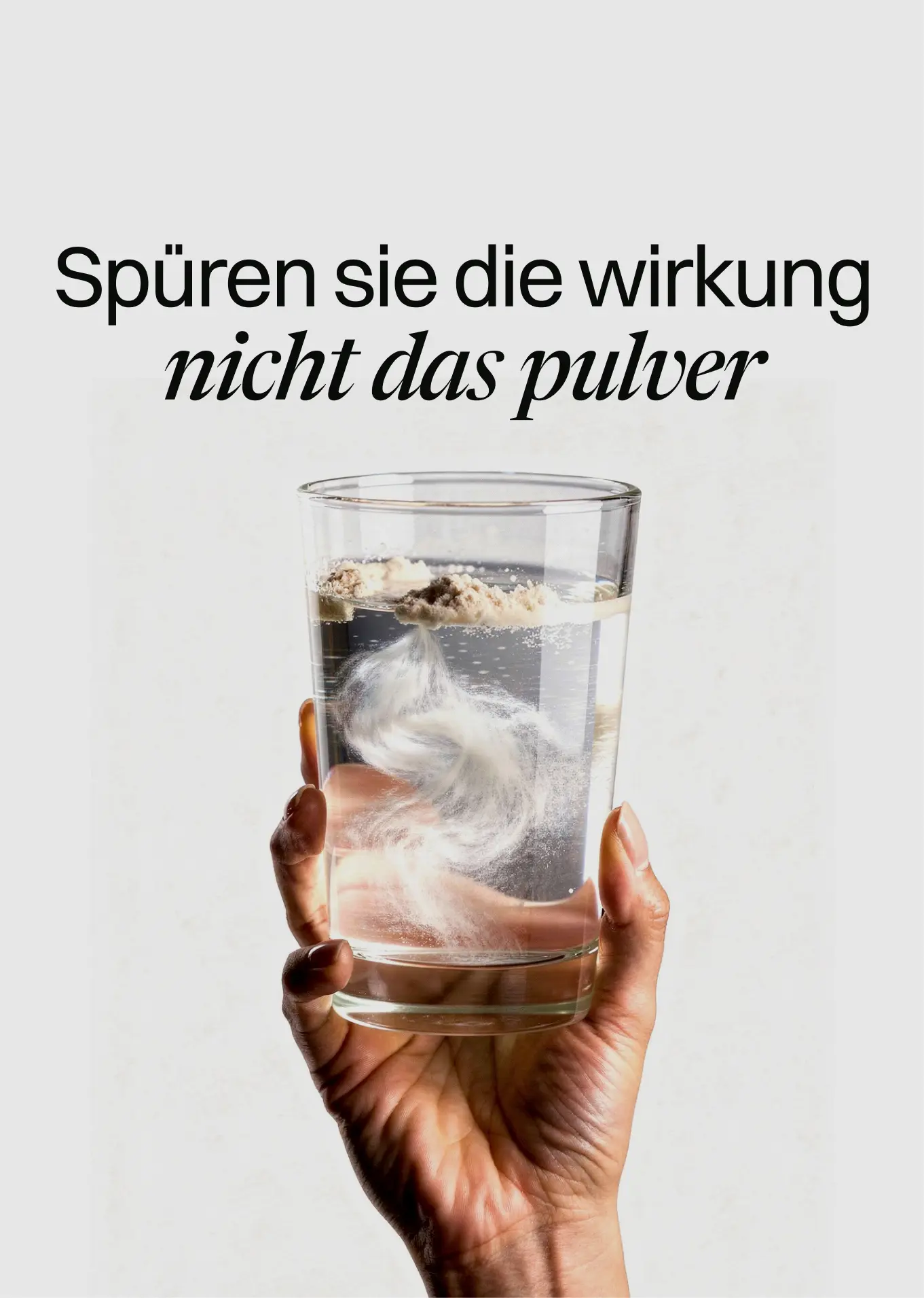 A hand holds a glass of water with powder dissolving in it, under German text.