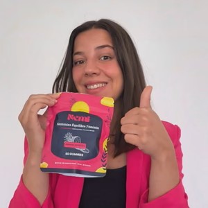 Person smiling, holding a packet of gummies, giving a thumbs-up.