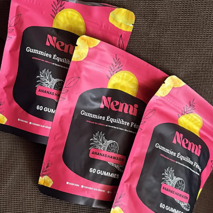 Three pink Nemi gummy packs with pineapple illustrations on a dark surface.